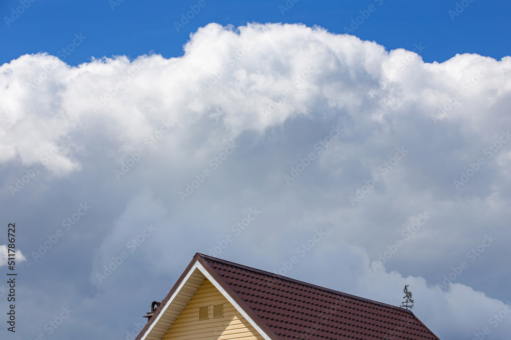 the roof of a residential building against a blue sky with clouds