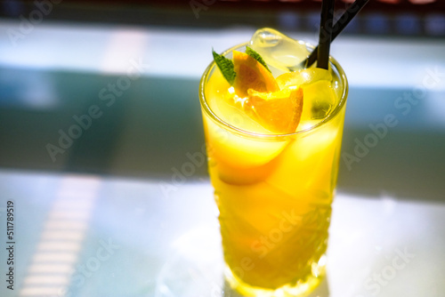 Fresh ice cold orange maraquia lemonade dressed with mint and orange slices in a glass under sunlight photo