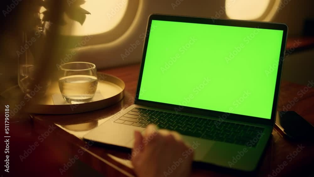 Woman watch green laptop screen on first class flight. Hands touch pad closeup
