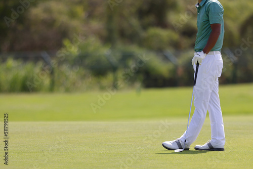 Golf player legs at golfing ball hole. Golfer posing on green lush course