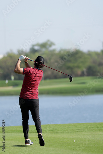 male golf player wearing red shirt hitting ball