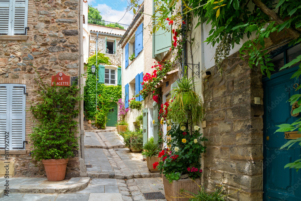Colorful red flowers and potted plants line the narrow streets of the Old Town area of the medieval village of Grimaud, France, in the hills above Saint-Tropez on the Cote d'Azur.