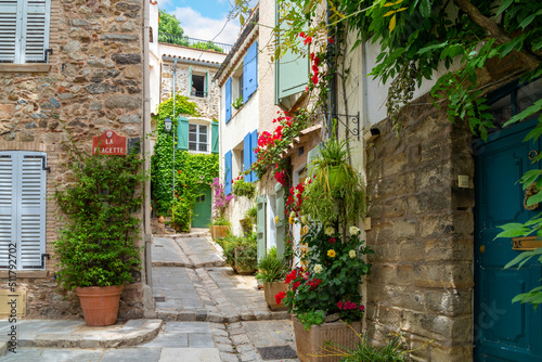 Colorful red flowers and potted plants line the narrow streets of the Old Town area of the medieval village of Grimaud, France, in the hills above Saint-Tropez on the Cote d'Azur. © Kirk Fisher