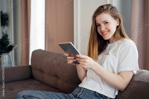 A woman uses a tablet at home on the couch