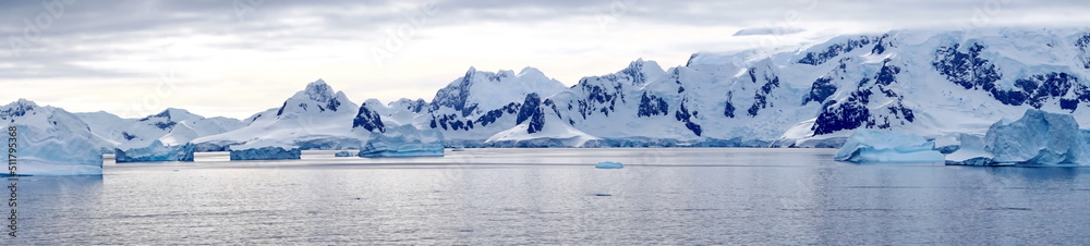 Panorama of icebergs floating in the bay, in front of snow covered moutains at Portal Point in Antarctica