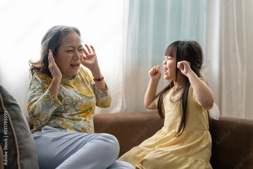 Shocked grandma closing ears not to hear noisy stubborn fussy little granddaughter screaming demanding attention, preschool spoiled kid girl yelling at grandmother, child tantrum manipulation concept