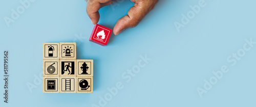 Hand choose cube wooden block stack with fire icon and door exit sing or fire escape with prevent icon and fire extinguisher and emergency prevention or protection symbol for safety and rescue. photo