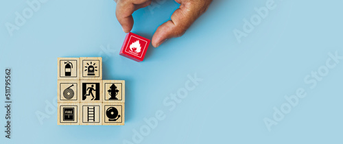 Quadro su tela Hand choose cube wooden block stack with fire icon and door exit sing or fire escape with prevent icon and fire extinguisher and emergency prevention or protection symbol for safety and rescue
