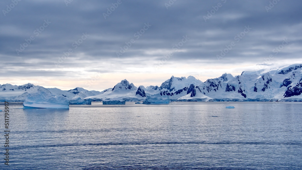 Icebergs floating in the bay in front of snow covered mountains at Portal Point in Antarctica Icebergs floating in the bay in front of snow covered mountains at Portal Point in Antarctica