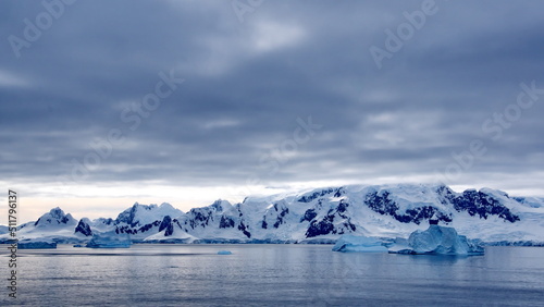 Icebergs floating in the bay in front of snow covered mountains at Portal Point in Antarctica © Angela