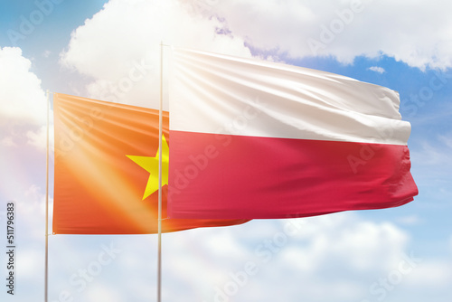 Sunny blue sky and flags of poland and vietnam