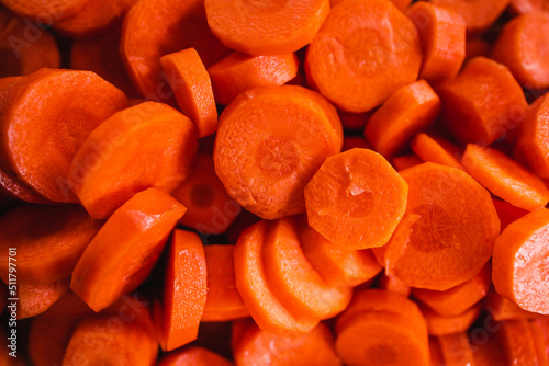 close-up of fresh carrots getting sliced on wooden chopping board, simple ingredients concept