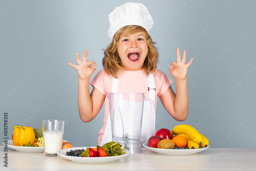 Child chef cook prepares food on isolated grey studio background. Kids cooking. Teen boy with apron and chef hat preparing a healthy vegetables. Excited funny chef cook. Child chef cook prepares food on isolated grey studio background. Kids cooking. Teen boy with apron and chef hat preparing a healthy vegetables. Excited funny chef cook.