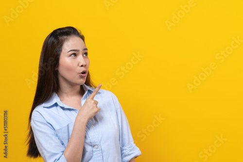 Shock asian young woman pointing finger up with surprise facial expression.