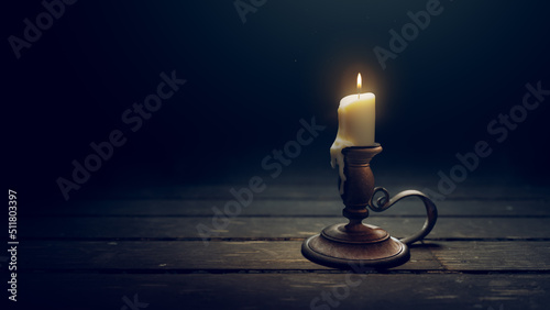 Antique brass candle holder with a burning candlestick on a dark wooden background. 3D rendering, illustration photo