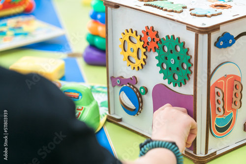 Mom's hand shows the child how to use a busybord photo