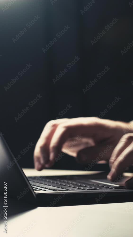 Night remote work. Online job. Freelancer lifestyle. Unrecognizable man hands typing on laptop late at dark workplace with free space. Vertical video. Night remote work. Online job. Freelancer lifestyle. Unrecognizable man hands typing on laptop late at dark workplace with free space. Vertical video.