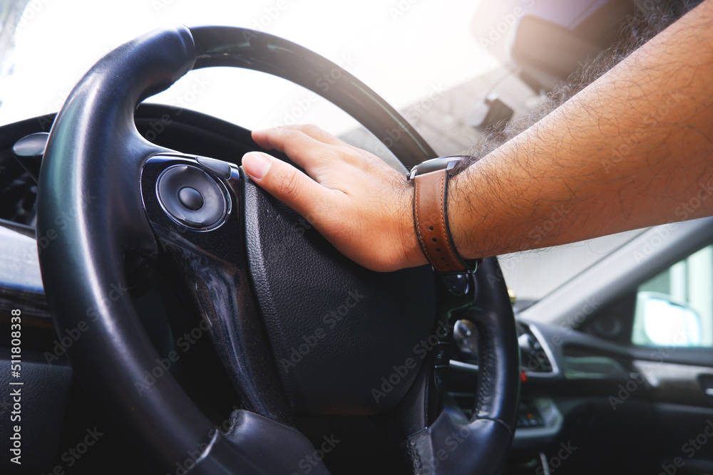 Naklejka premium Driver hand pressing on steering wheel honking horn