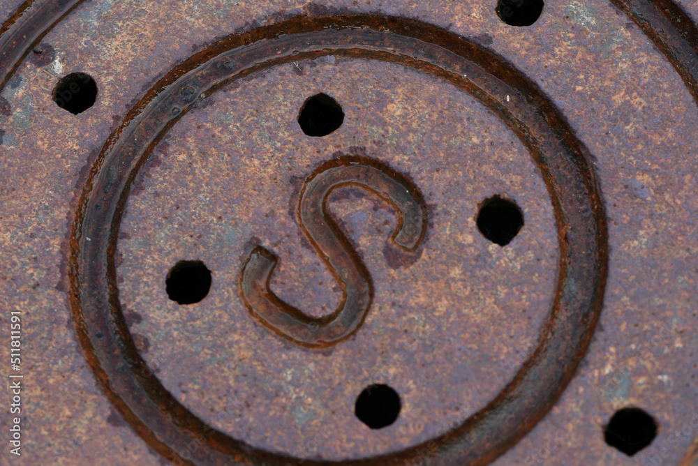 rusty manhole cover with 'S