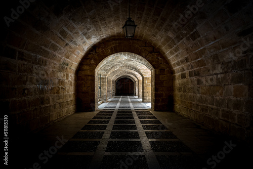 Architecture photography with converging lines from dark to light of vaulted passage in the walls below Royal Palace of la Almudaina called Palau Reial de l'Almudaina in Palma de Mallorca.