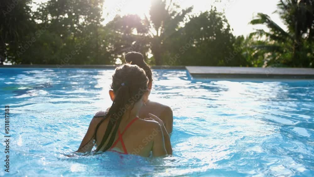 Happy caucasian mother and her cute daughter swim in the pool on sunny tropical island. slow motion. 4k Happy caucasian mother and her cute daughter swim in the pool on sunny tropical island. slow motion. 4k
