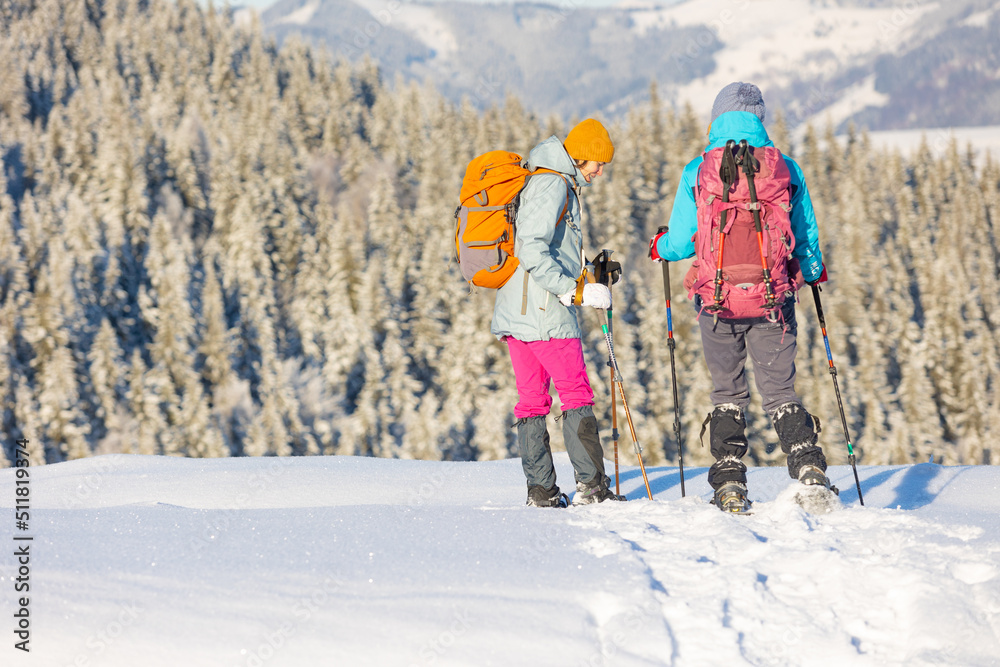 Two women walk in snowshoes on the mountain trail Two women walk in snowshoes on the mountain trail