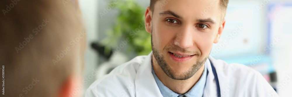 Fototapeta premium Young male doctor listens to a patient, close-up face