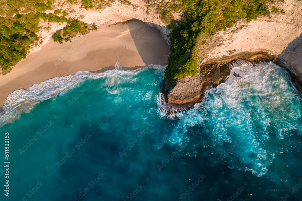 Aerial drone top view shot of rocky beach with cliff. Indian ocean shore. Copy space for text. Nature and travel background. Beautiful natural summer vacation travel concept. Waves and sand.