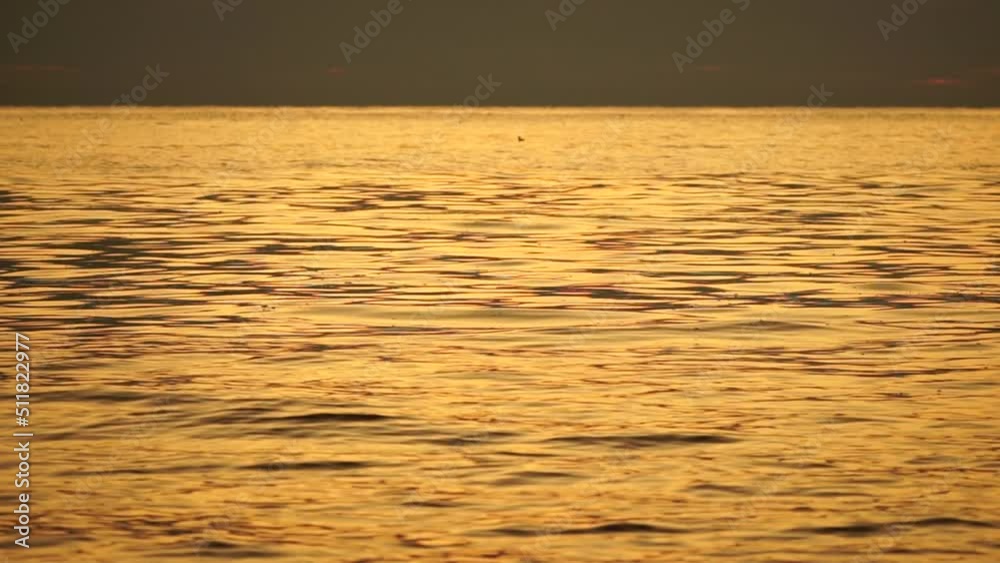 Abstract nature summer ocean warm sunset sea background. Small waves on water surface in motion blur with bokeh lights from sunrise. Holiday, vacation and recreational background concept. Slow motion Abstract nature summer ocean warm sunset sea background. Small waves on water surface in motion blur with bokeh lights from sunrise. Holiday, vacation and recreational background concept. Slow motion