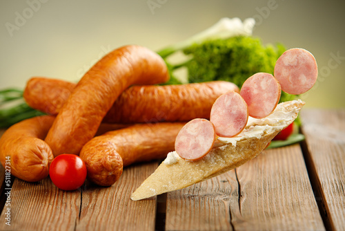 Appetizing sandwich made of freshly baked, crunchy bread with Krakowska dried sausage. Levitating sandwich with kielbasa and vegetables on the back photo