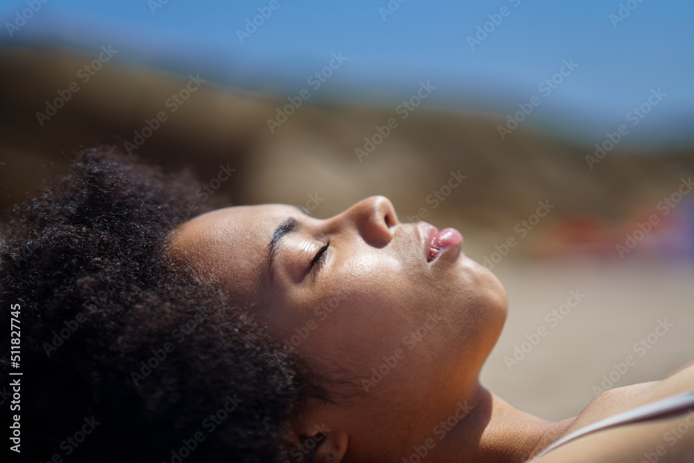 Young African American woman lying on beach with closed eyes Young African American woman lying on beach with closed eyes