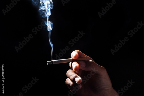 close up of man hand holding cigarette on black background