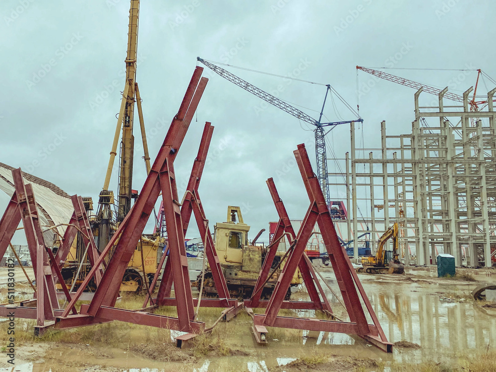construction site of an industrial complex. red structures stacked together for fall protection. long metal sticks for building foundations and strengthening buildings construction site of an industrial complex. red structures stacked together for fall protection. long metal sticks for building foundations and strengthening buildings