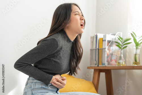 Flatulence asian young woman, girl hand in stomach ache, suffer from food poisoning, abdominal pain and colon problem, gastritis or diarrhoea. Patient belly, abdomen or inflammation, concept. photo