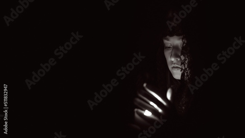 Woman in a black hood with a lit candle in her hands, black and white photo