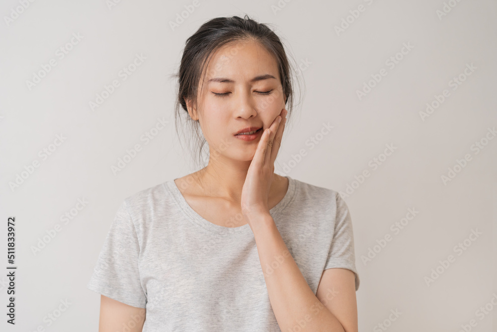 Closing eyes asian young woman touching cheek, face expression from toothache, tooth decay or sensitivity, Having tooth or teeth problem or inflammation, suffering from health. Sensitive teeth people Closing eyes asian young woman touching cheek, face expression from toothache, tooth decay or sensitivity, Having tooth or teeth problem or inflammation, suffering from health. Sensitive teeth people