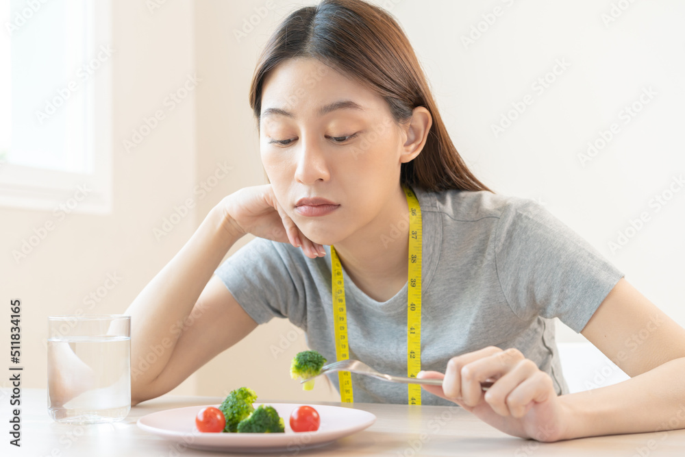 Anorexia, unhappy beautiful asian young woman, girl on dieting, holding fork at broccoli in salad plate, dislike or tired with eat fresh vegetables. Nutrition of good healthy, bored with food. Anorexia, unhappy beautiful asian young woman, girl on dieting, holding fork at broccoli in salad plate, dislike or tired with eat fresh vegetables. Nutrition of good healthy, bored with food.