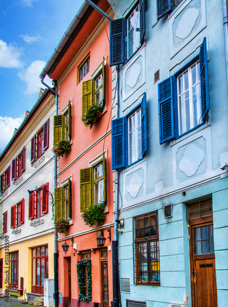 Exterior of apartment buildings
with balconies. Selective Focus. Buildings And Streets Of A Romanian City Called Sibiu. Windows Of Antique Buildings With Colourful Walls And Shutters. Architecture.