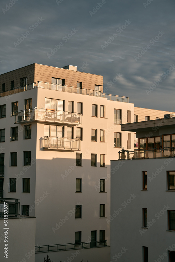 The apartment building at sunset. Condominium construction in the evening. Strong sunlight falls on the low-rise modern residential building
