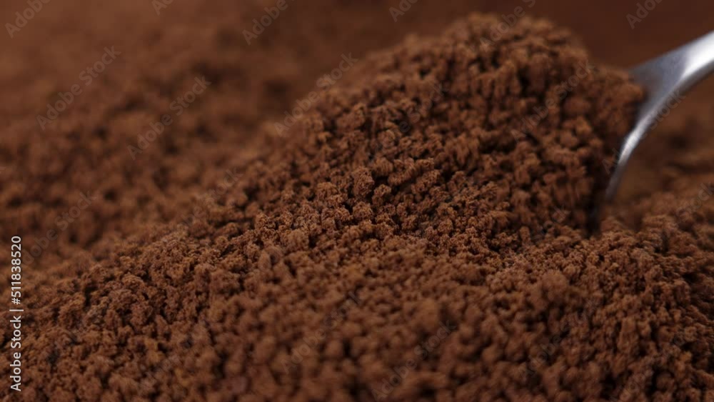 Instant granulated coffee falling from a teaspoon in slow motion close up