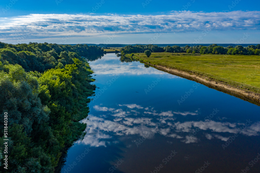Aerial  view of a beautiful summer  landscape over river while dawn. Top view over river with a smooth water surface reflecting blue sky and clouds.