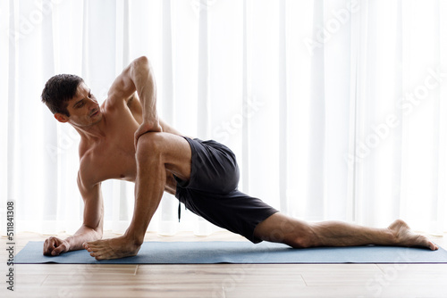Young yoga man doing stretching legs during morning routine