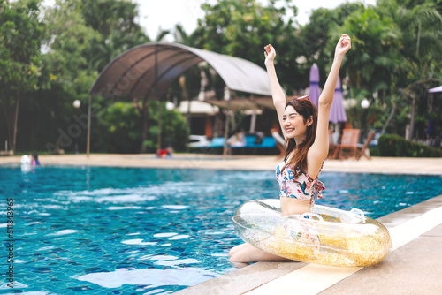 Raised hand young adult asian woman at hotel swimming pool holidays summer travel #511843965