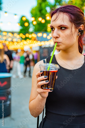 young woman holding a plastic glass with a drink on the street