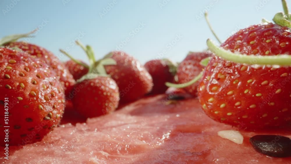 Strawberries in a row lie on a cut watermelon, against a blue sky. Dolly slider extreme close-up. Laowa Probe. Slow mo Strawberries in a row lie on a cut watermelon, against a blue sky. Dolly slider extreme close-up. Laowa Probe. Slow mo