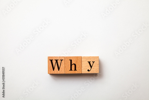 Whyの文字。なぜ。疑問符。3つの木製ブロックに書かれている。黒い文字。白い背景。