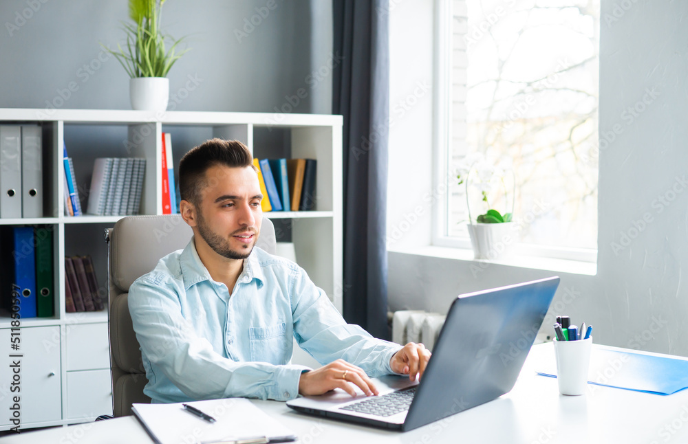 Young Man Works while Sitting in front of a Computer at Home. The Workplace of a Professional Worker, Freelancer or Student. Distance Work and Education Concept. Young Man Works while Sitting in front of a Computer at Home. The Workplace of a Professional Worker, Freelancer or Student. Distance Work and Education Concept.