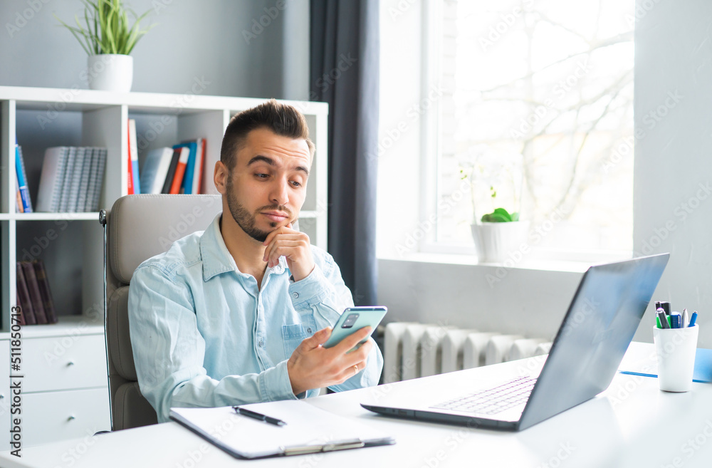 Young Man Works while Sitting in front of a Computer at Home. The Workplace of a Professional Worker, Freelancer or Student. Distance Work and Education Concept. Young Man Works while Sitting in front of a Computer at Home. The Workplace of a Professional Worker, Freelancer or Student. Distance Work and Education Concept.