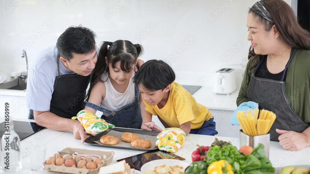Happy family cooking together on kitchen with kids. Young family cooking.