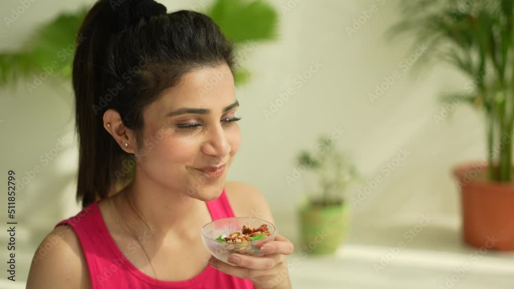Indian young woman eating sprouts and museli healthy food in breakfast while doing yoga in morning.Asian beautiful female doing exercise and take nutrition in breakfast.healthy concept.female fitness.